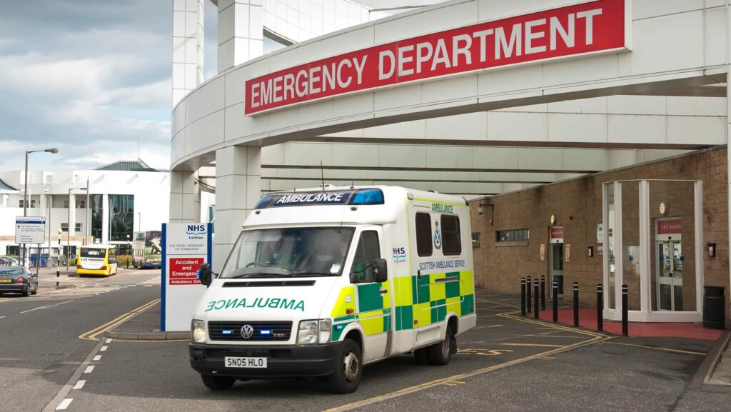 A moving emergency ambulance outside a hospital A & E accident and emergency department.